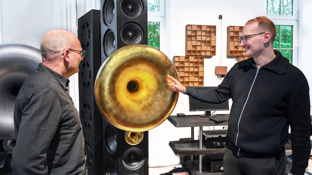 Hingucker sind in dem Showroom natürlich die Hornlautsprecher und hier insbesondere die imposante Topline Bob XL mit ihrem großen goldglänzenden Trichter. Sebastian Stein (rechts) erklärt lite-Redakteur Volker Frech (links), wie Aufwändig die Fertigung des Horns ist und wie filigran seine Fixierung: Im Prinzip hängt das Horn an einer Gitarrensaite.